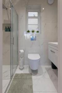 a white bathroom with a toilet and a shower at Luxury Apartment in Willesden in London