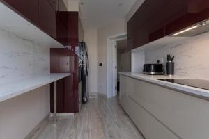 eine Küche mit weißen Arbeitsplatten und Holzböden in der Unterkunft Luxury Apartment in Willesden in London