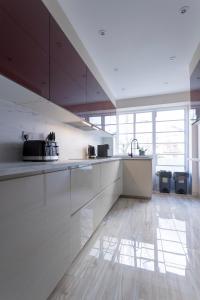 eine Küche mit weißen Schränken und einem großen Fenster in der Unterkunft Luxury Apartment in Willesden in London