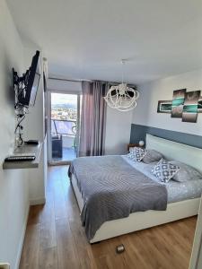 a bedroom with a bed and a window and a chandelier at Appartement T2 Prado Chanot Plage Marseille in Marseille