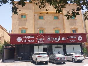 Dos coches aparcados delante de un edificio en Nuzul Altoot Apartments نزل التوت, en Riad