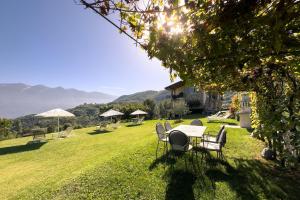 een tafel en stoelen in een tuin met bergen op de achtergrond bij Mos Country House in Tremosine Sul Garda