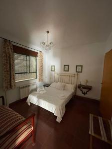 ein Schlafzimmer mit einem weißen Bett und einem Fenster in der Unterkunft Agradable casa con jardín y chimenea interior in Baena