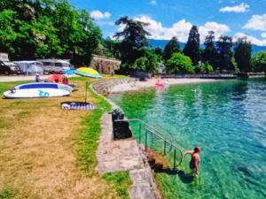 a man standing in the water at a beach at Petit St George 100mt du lac a Montreux in Montreux