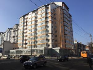 a tall building with cars parked in front of it at Apartment on Belvedere in Ivano-Frankivsk