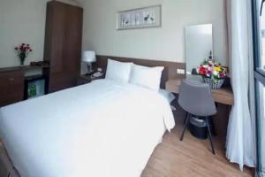 une chambre avec un lit, un bureau et une chaise dans l'établissement Tigon Hotel - 148 Nguyễn Chánh HN by - BAY LUXURY, à Hanoï 2 autres photos
