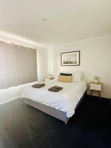 a white bedroom with a bed with two towels on it at Island Villas - Lady Elliott - Unit 2 in Bundaberg
