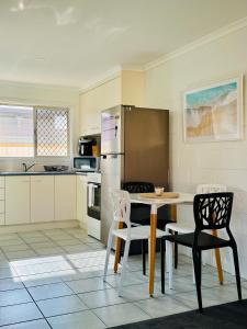 a kitchen with a table and chairs and a refrigerator at Island Villas - Lady Elliott - Unit 2 in Bundaberg