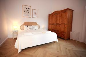 a bedroom with a large white bed and a wooden cabinet at PATRU Apartment in Cluj-Napoca