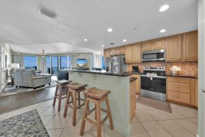 a kitchen with a bar with stools and a living room at Palazzo 408 in Panama City Beach
