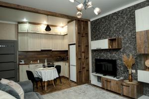 cocina y sala de estar con mesa y TV en Люкс в ЖК Green City Park, en Karagandá