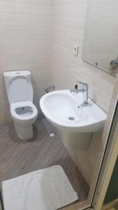 a white bathroom with a toilet and a sink at Access Hotel in Baku