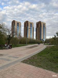 dos edificios altos en un parque con gente caminando en Люкс в ЖК Green City Park, en Karagandá