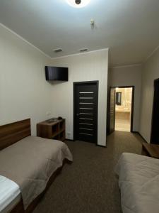 1 dormitorio con 2 camas y TV en la pared en Status Hotel en Poltava