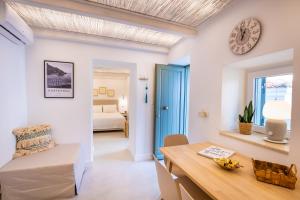 a living room with a table and a clock on the wall at Valandou Guesthouses - Boutique Apartments in Aperi, Karpathos in Karpathos +64 photos