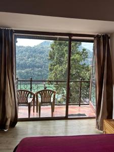 a room with a view of a balcony with two chairs at Panoramic View of Lake close to Mall Road - Oasis in Nainital