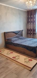 1 dormitorio con cama y alfombra en el suelo en 1 комнатная квартира в Павлодаре, en Pavlodar