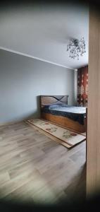 a bedroom with a bed and a wooden floor at 1 комнатная квартира в Павлодаре in Pavlodar