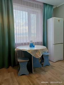 a table in a kitchen with a white refrigerator at 1 комнатная квартира в Павлодаре in Pavlodar