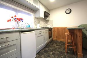 una cocina con armarios blancos y un reloj en la pared en 23 Fairfield, en Inverness