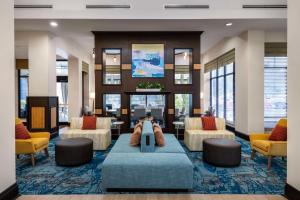 Hilton Garden Inn West Palm Beach Airport في ويست بالم بيتش: لوبي فيه كنب وكراسي في فندق