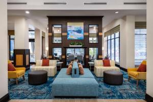 a lobby with couches and chairs in a hotel at Hilton Garden Inn West Palm Beach Airport in West Palm Beach