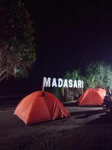 dos paraguas rojos delante de una señal de madama en fardan Tenda camping madasari, en Pangandaran