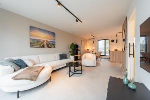 ein Wohnzimmer mit einem weißen Sofa und einem Tisch in der Unterkunft NIEUW De Grenspaal ZUID 2slpk - 4P - SAUNA - LAADPAAL in Riemst