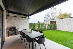 a patio with a table and chairs and a grill at NIEUW De Grenspaal ZUID 2slpk - 4P - SAUNA - LAADPAAL in Riemst