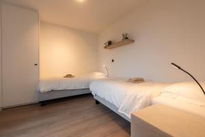 2 Betten in einem Zimmer mit weißen Wänden und Holzböden in der Unterkunft NIEUW De Grenspaal ZUID 2slpk - 4P - SAUNA - LAADPAAL in Riemst