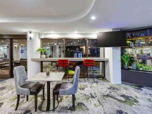 a bar with red chairs and a table in a room at Mercure Penrith in Penrith