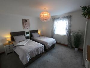 a bedroom with two beds and a chandelier at Cribyn Lodge in Brecon