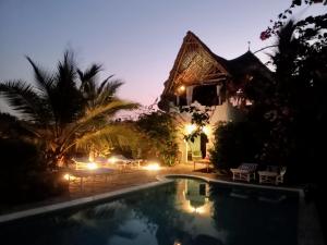 a pool in front of a house at night at HUHURU House in Watamu