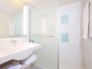 a white bathroom with a shower and a sink at Novotel Wien Hauptbahnhof in Vienna