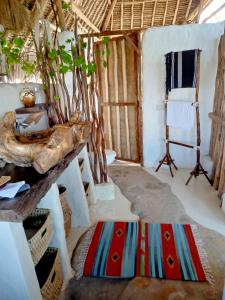 a room with a table and a chair and a rug at HUHURU House in Watamu