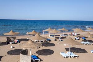 a beach with chairs and umbrellas and the ocean at Calimera Blend Paradise in Hurghada