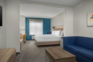 グリーンズボロにあるHoliday Inn Express Hotel & Suites Greensboro - Airport Area, an IHG Hotelのベッドとソファ付きのホテルルーム