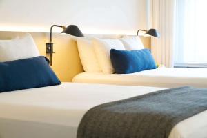 two beds with blue pillows in a hotel room at Ambassador Chicago, part of JdV by Hyatt in Chicago