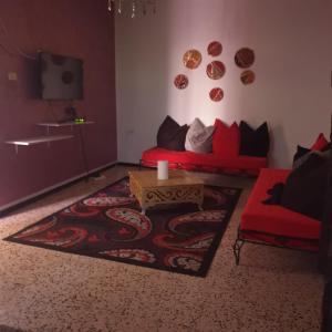 a living room with a red couch and a table at Dar kouka in Tataouine