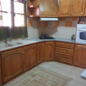 a kitchen with wooden cabinets and a sink and a microwave at Dar kouka in Tataouine