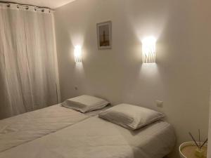 - une chambre avec deux lits et deux lumières sur le mur dans l'établissement Village apartment with character, à Saint-Hippolyte