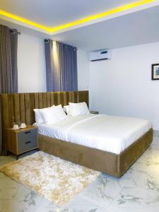 a bedroom with a large bed with a wooden headboard at Omah Apartments in Abuja