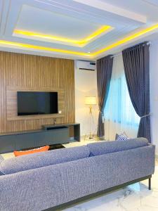 a living room with a couch and a tv at Omah Apartments in Abuja