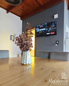 a vase of flowers sitting on a wooden table at Firmat Apart Premium Estadías confortables para empresas y familias in Firmat