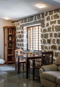 ein Esszimmer mit einem Tisch und einer Steinmauer in der Unterkunft Jungle stay by Bilwa Estate in SanivÄrsante