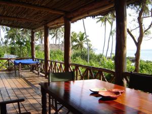 ein Holztisch auf einer Veranda mit Blick auf das Meer in der Unterkunft FULLY PRIVATE VILLA 390sqm ZERO MINUTES TO BEACH MATEMWE in Gazija