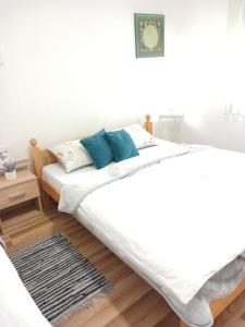 uma cama com lençóis brancos e almofadas azuis num quarto em Apartman Villa Vita em Capljina