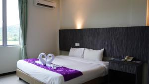 a hotel room with a bed with a bow on it at Salsa Resort Langkawi By Casa Loma in Pantai Cenang