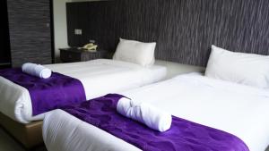 two beds in a hotel room with purple sheets at Salsa Resort Langkawi By Casa Loma in Pantai Cenang