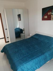 ein Schlafzimmer mit einem blauen Bett und einem Spiegel in der Unterkunft Casa del sole in Montalbano Ionico